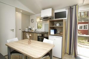 a kitchen with a wooden table and a table and chairs at Tiny Chalet Nr 820 in Göhren +15 photos