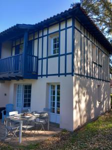 a house with a table and chairs in front of it at Maison les pieds dans l'eau, piscine et plage à pieds in Moliets-et-Maa