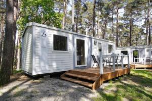 a white tiny house with a table and chairs at Tiny Chalet Nr 814 in Göhren