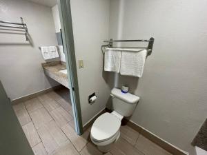a bathroom with a toilet and a sink with towels at Budget Inn Ada in Ada