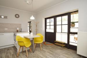 a kitchen with yellow chairs and a table in a room at Haus Büdnerstube Ferienwohnung Nr 3 - mit Schwimmbad und Saunanutzung im AHOI-Erlebnisbad Sellin in Middelhagen