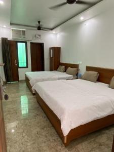 une chambre avec trois lits dans une pièce dans l'établissement Kisna Dham by YatriMap, à Haridwar