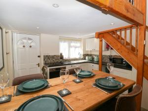 a wooden table with green plates and wine glasses at Harvest Moon Cottage in Bishops Frome +10 photos