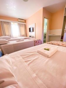 a hotel room with four beds with white sheets at Hotel Paradouro - Com Café da Manhã in Alfredo Wagner