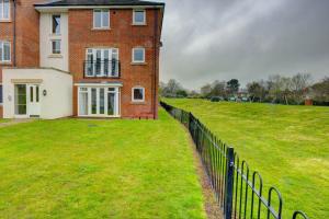 a brick house with a fence in front of it at 2-BR Executive En-Suite Apartment by MBiZ in Coventry