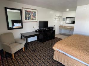 a hotel room with a bed and a desk and a bed at Budget Inn Ada in Ada