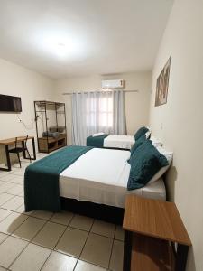 una habitación de hotel con dos camas y una mesa en Della Foz, en Foz do Iguaçu