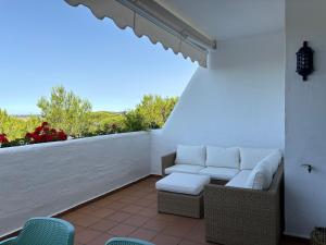 a patio with a couch and chairs on a white wall at Luxury Hacienda Golf Islantilla in Islantilla
