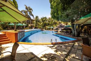 a swimming pool with chairs and umbrellas in a resort at Solar Pipa - Solar da Gameleira Flats in Pipa