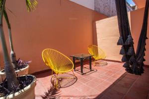three yellow chairs and a table on a patio at Hotel Tropicus Boutique in Puerto Vallarta
