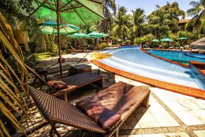 una piscina con sillas y sombrillas junto a un complejo en Solar Pipa - Solar da Gameleira Flats en Pipa