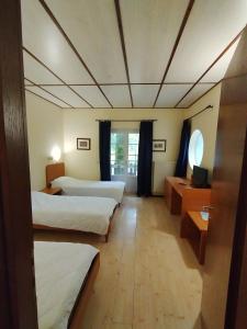 Habitación de hotel con 3 camas y escritorio. en HOTEL VILLA MABULTON 2.0 en Chiasiéllis