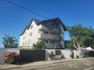 a large white building with a fence in front of it at Sunshine Costinești in Schitul