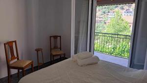 a bedroom with a bed and two chairs and a large window at Heirlooms and Halos in Monastiraki