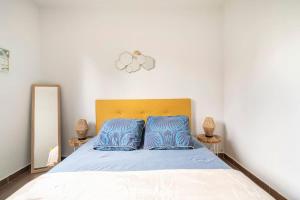 a bedroom with a bed with blue pillows and a mirror at Appartement avec Jardin et Terrasse près de Paris in Mantes-la-Jolie