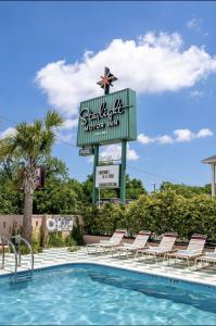 una piscina en un hotel con un cartel y sillas en The Starlight Motor Inn en Charleston