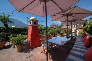 a patio with a red lighthouse and tables and umbrellas at Posada del Angel in Antigua Guatemala