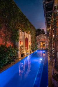 a large swimming pool with blue water at night at Posada del Angel in Antigua Guatemala