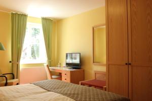 a bedroom with a bed and a desk with a television at Landgasthof Wildwasser in Wolthausen