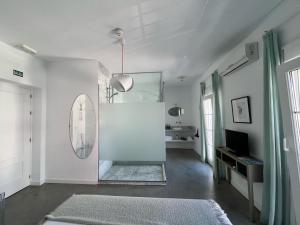 Habitación blanca con espejo y TV en Chipibeach, Hostal Boutique, en Chipiona