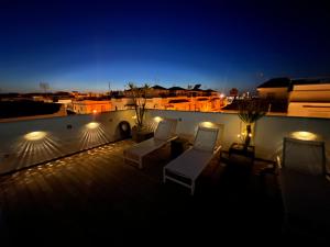 a rooftop deck with chairs and lights at night at Chipibeach, Hostal Boutique in Chipiona