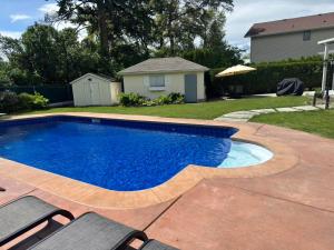 a swimming pool with two chairs and a house at Park side Basement 2 bedroom suite in Kelowna