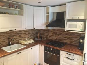 a kitchen with white cabinets and a sink and a microwave at Cottage House in Pača +18 photos