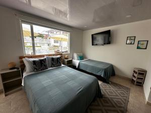 1 Schlafzimmer mit 2 Betten und einem TV an der Wand in der Unterkunft Kalathea Casa in Tocaima