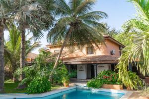 a house with a swimming pool and palm trees at Keur Touty ! in Sali Tapé