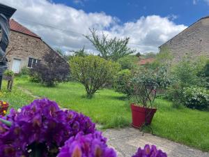 un jardin avec des fleurs violettes dans une cour dans l'établissement La BOCQUILLONNE, 