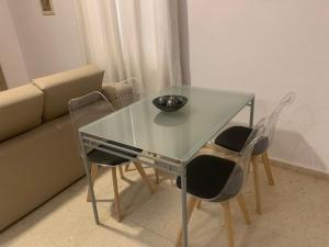 a glass table with two chairs and a bowl on it at Casa Luli in Torreguadiaro