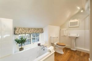 a white bathroom with a toilet and a window at Hollins Farmhouse in Leyburn +25 photos