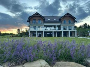 a large house with purple flowers in front of it at Skalnica - Apartamenty w Bieszczadach nad Soliną in Berezka