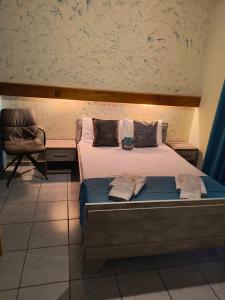 a bedroom with a bed and a chair at Amelies Apartments in Paralia Katerinis