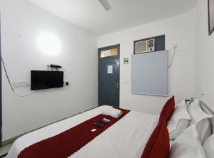 1 dormitorio con 1 cama, TV y puerta en Hotel Hauz Khas Fort View en Nueva Delhi