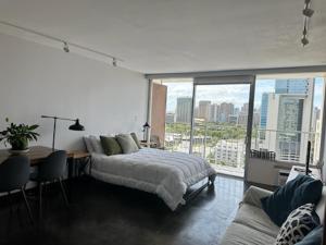 a bedroom with a bed and a desk and a large window at Marine Surf Waikiki in Honolulu