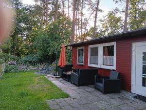 een rood huis met een patio met een parasol en stoelen bij Bungalow 2 am Donnerberg in Sewekow in Sewekow