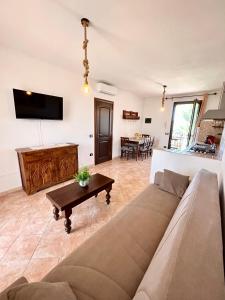 ein Wohnzimmer mit einem Sofa und einem Tisch in der Unterkunft Il tramonto tra Alghero e Stintino in Palmadula