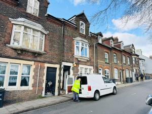 a person standing next to a white van parked on a street at Luton Centre Apartment in Luton