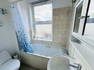 a bathroom with a tub and a toilet and a sink at Luton Centre Apartment in Luton +9 photos