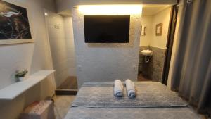 a bathroom with a tv on the wall and a towel at Angel Hospedagem de quartos in Vila Velha