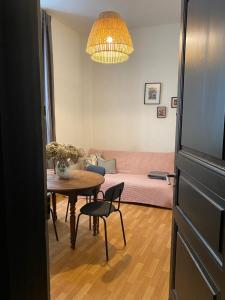a living room with a table and a pink couch at Grand studio style bordelais dans le triangle d'or in Bordeaux