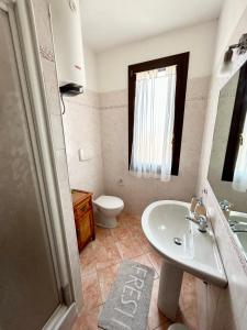 ein Badezimmer mit einem weißen Waschbecken und einem WC in der Unterkunft Il tramonto tra Alghero e Stintino in Palmadula