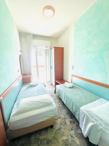 una camera con due letti e una finestra di Hotel Vernel a Rimini