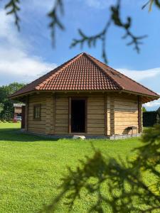 ein kleines Holzhaus auf einem Grasfeld in der Unterkunft Ziedu pirts in Auciems