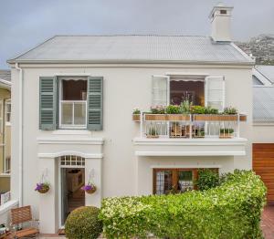 a white house with a balcony with flowers at The Majestic Apartments Luxury Private Rental 8 Middedorp in Kalk Bay