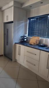 Una cocina con gabinetes blancos y un refrigerador de acero inoxidable. en Nelspruit holiday house, en Mataffin