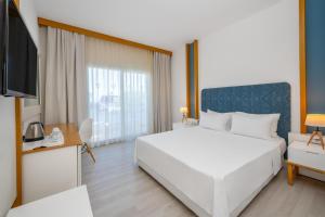 a bedroom with a large white bed and a tv at Labranda TMT Bodrum in Bodrum City +157 photos