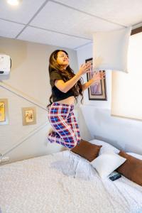 una mujer saltando sobre una cama en Villa 97 hostal económico cerca del aeropuerto, en Guayaquil