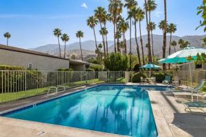 a swimming pool with a fence and palm trees at *Condo - 490 E Via Ensenada Cir, 92264 in Palm Springs